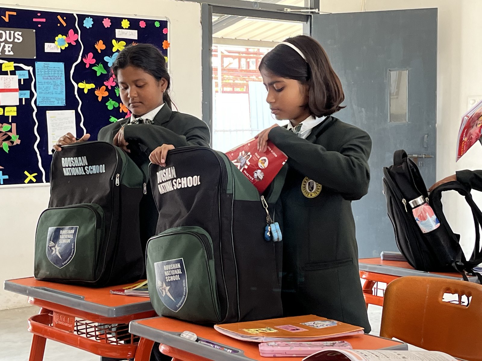 Students learning with books and digital resources at Roushan National School